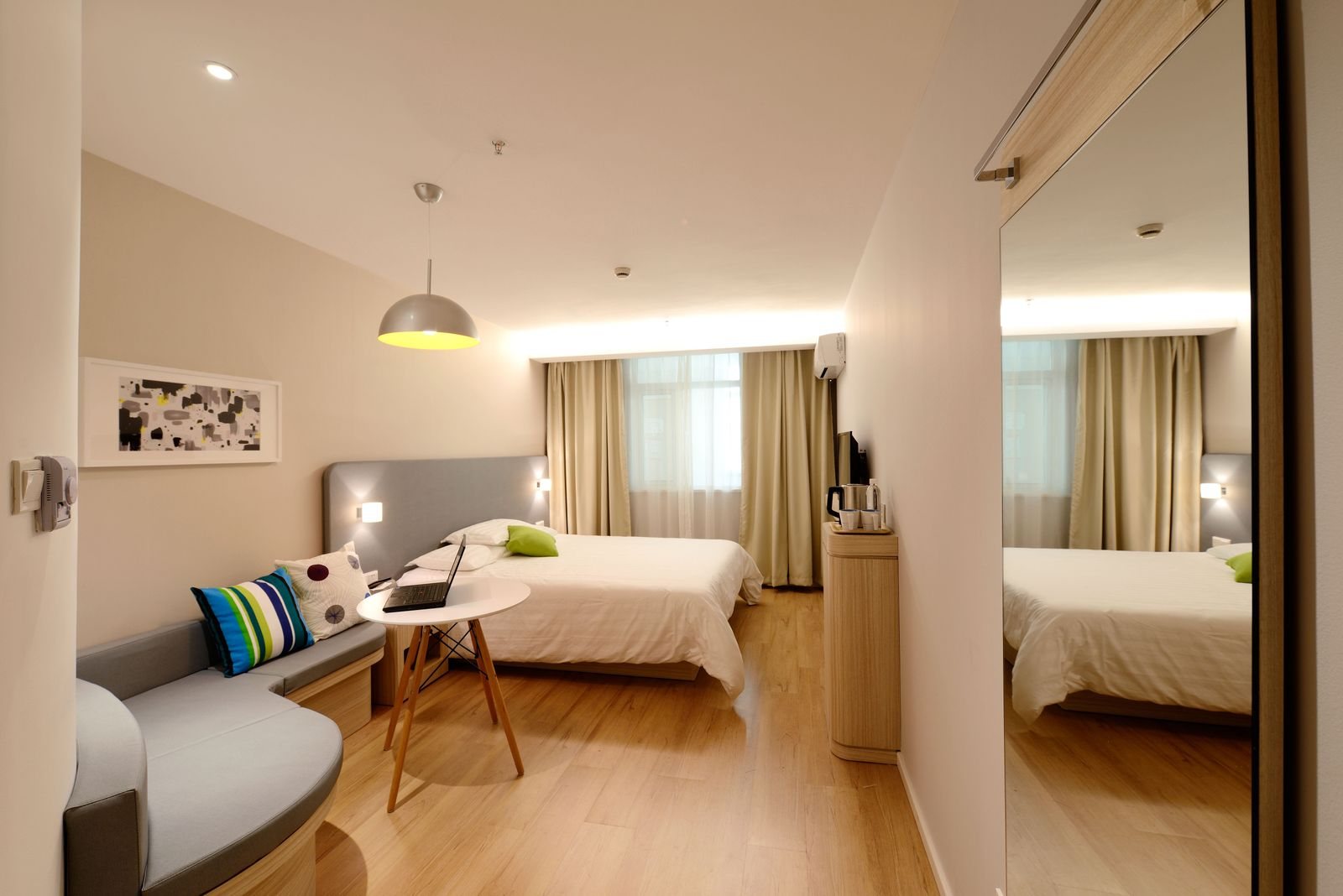 Contemporary double room with wooden flooring, a desk and a seating area